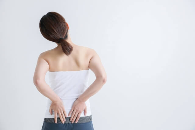腰を抑える女性背面